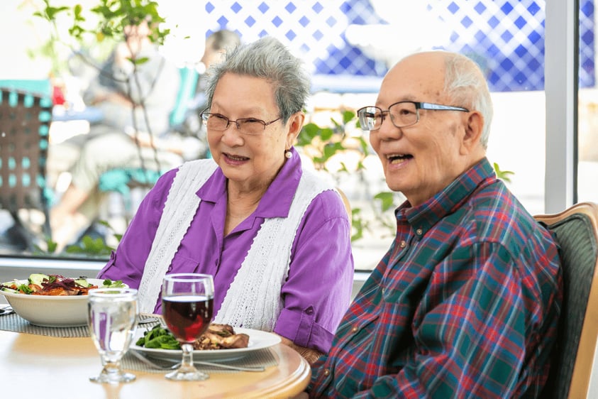 Senior couple with food and wine in the dining room at Westminster Gardens