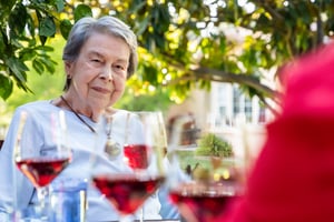 Senior woman sitting outside with glasses of red wine