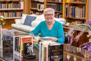 Senior woman with a book at a table in the library at Westminster Gardens