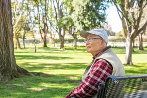 Senior man sitting on a bench on the grounds of Westminster Gardens