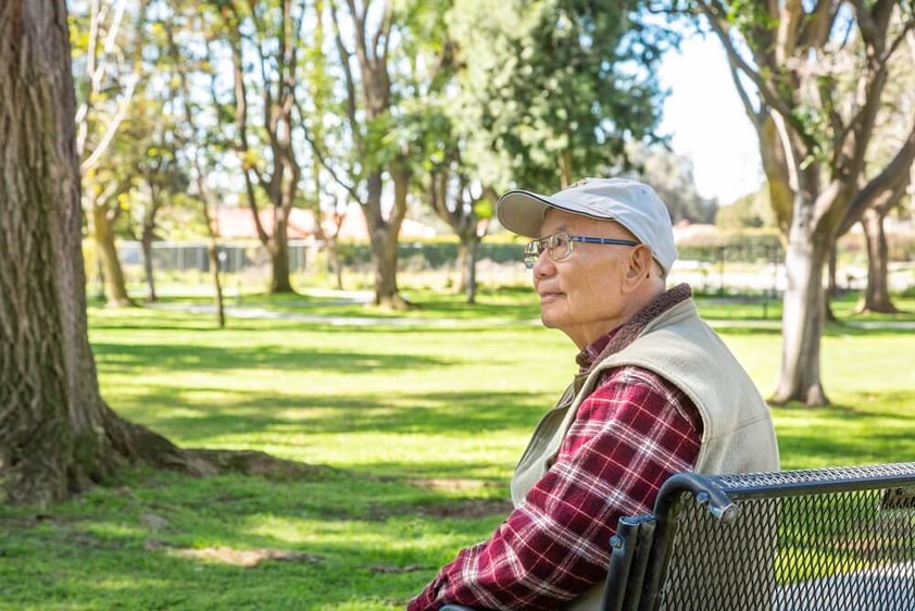 Senior man sitting on a bench on the grounds of Westminster Gardens