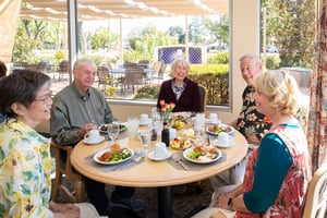 Five seniors enjoying a meal at a table in the dining room at Westminster Gardens