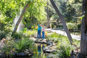 Two senior women — one pointing up — next to the pond at Westminster Gardens
