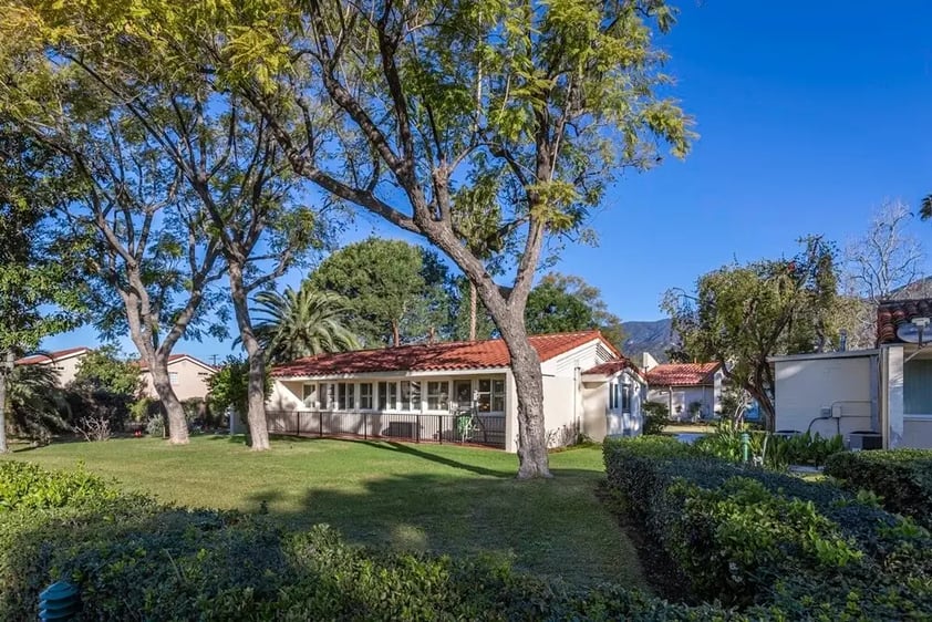Backyard of a single-story Westminster Gardens home with three large trees