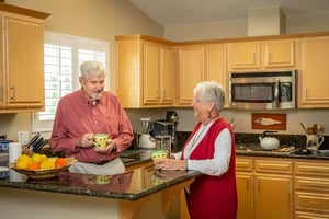Senior couple holding mugs in the kitchen of their Westminster Gardens home