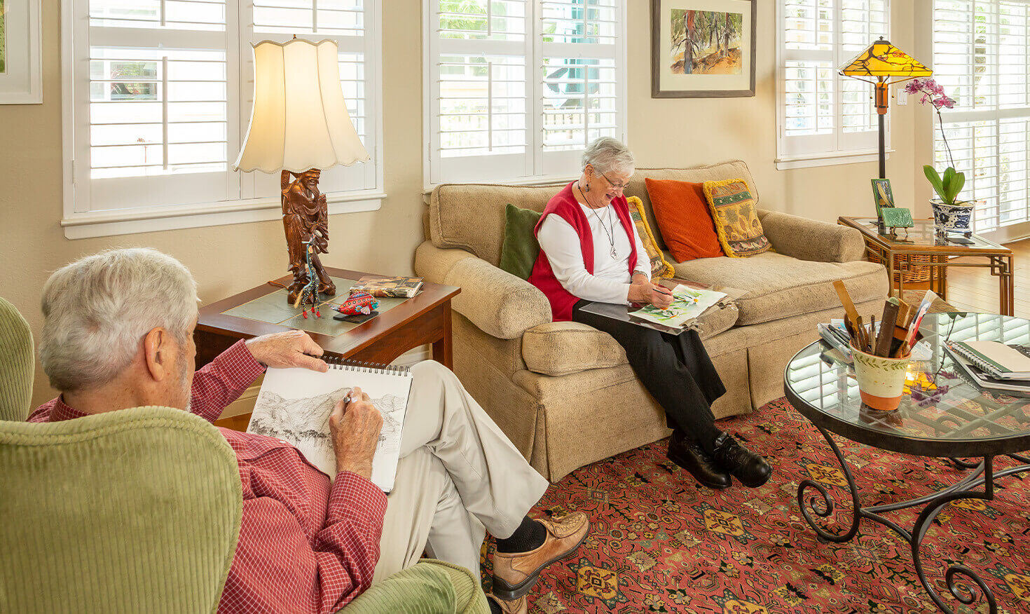 Senior couple drawing and sitting in the living room of their home at Westminster Gardens