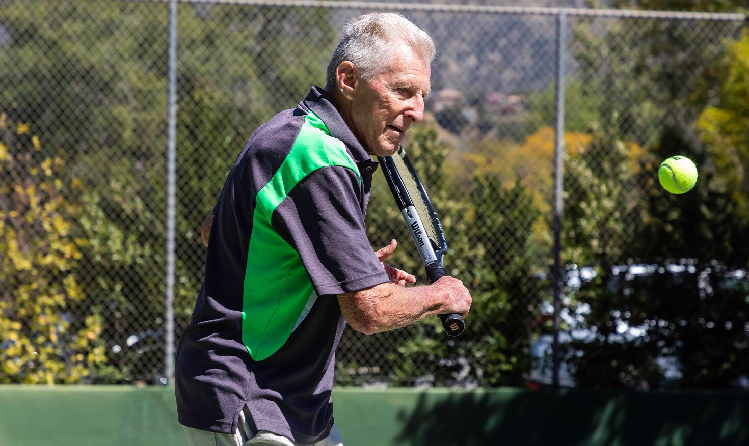 Senior man playing tennis on the Westminster Gardens tennis court