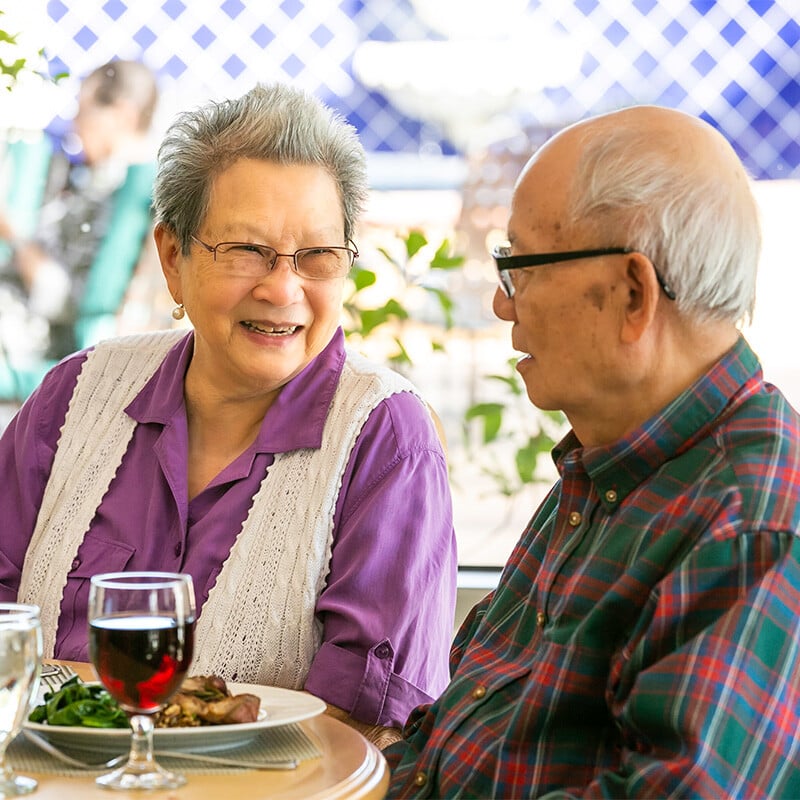 Senior couple with food and wine in the dining room at Westminster Gardens