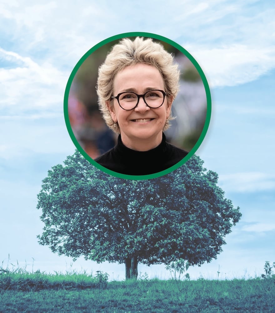 A tree under a blue sky with a circular portrait of a smiling person with glasses superimposed above it.