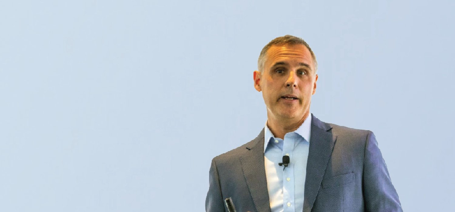 Dr. Chris Furmanski speaks into a microphone on a blue background.