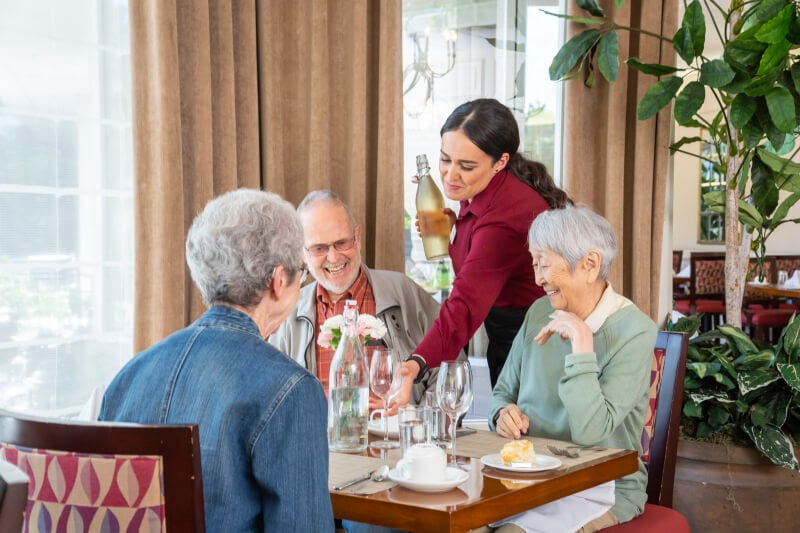 table of 3 in dinign room, being served wine