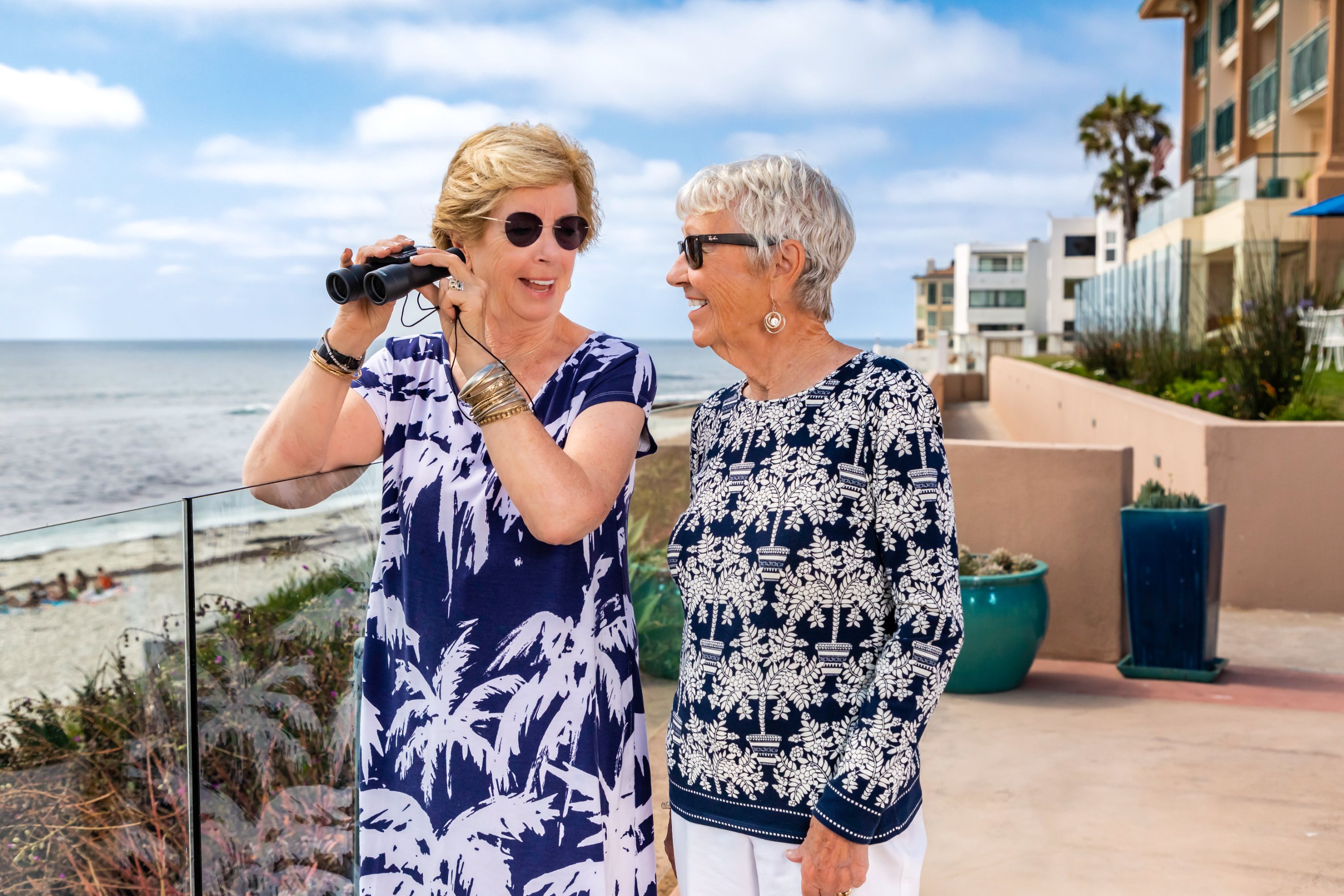 Two women looking at the beach with binoculars