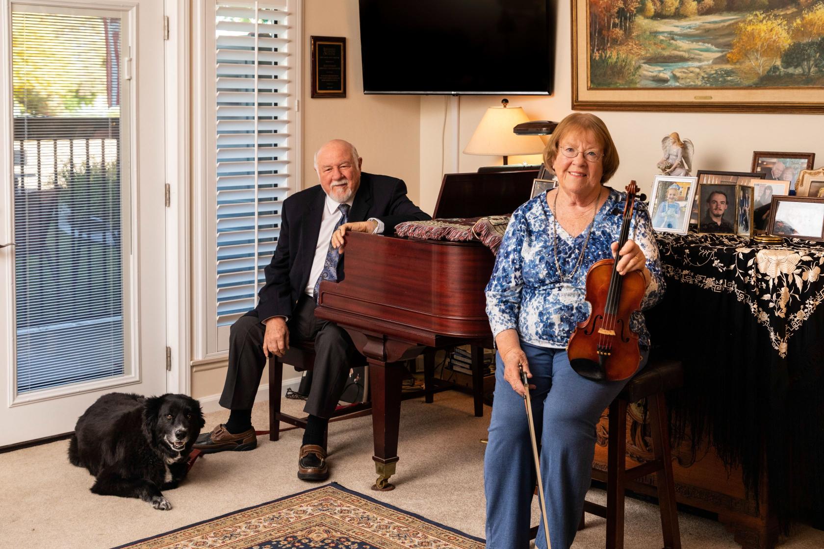 Man sitting close to a piano and lady holding a violin