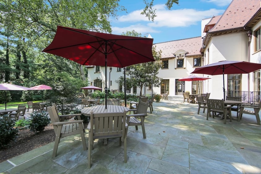 The Mansion at Rosemont's outdoor patio with tables, chairs, and red umbrellas