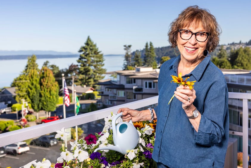 A resident tending flowers on a balcony with scenic views at Judson Park, a HumanGood community.