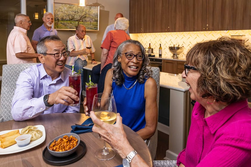 Residents gathering and socializing with drinks in a community kitchen space at Judson Park, a HumanGood community.