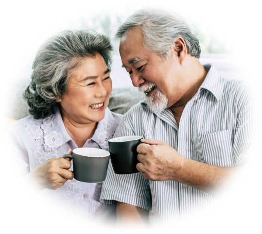 A smiling couple shares a moment while holding coffee mugs.