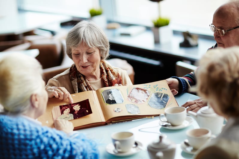 Woman shares a photo album with friends at a café.