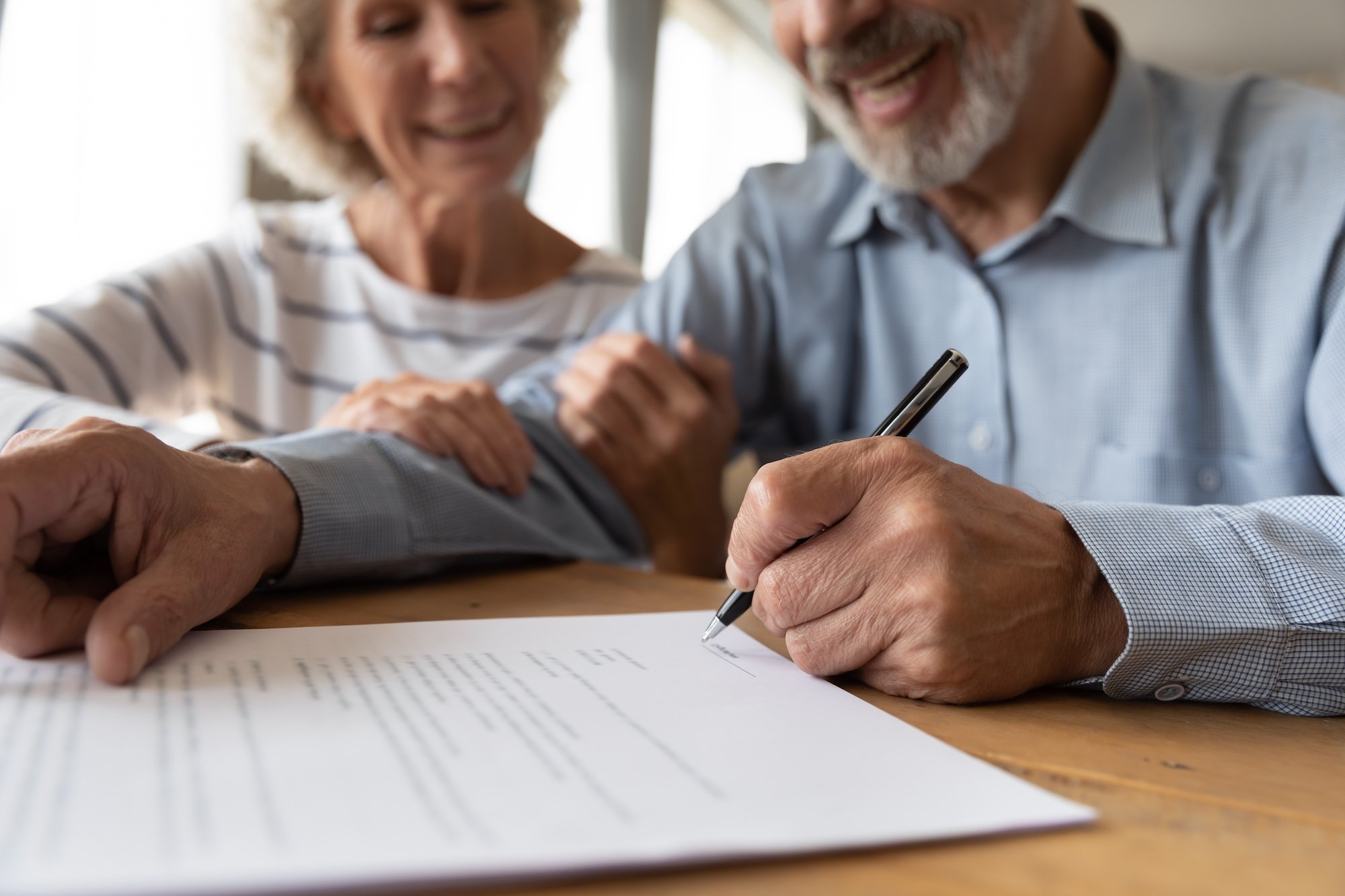 senior man and woman smiling while they write their will