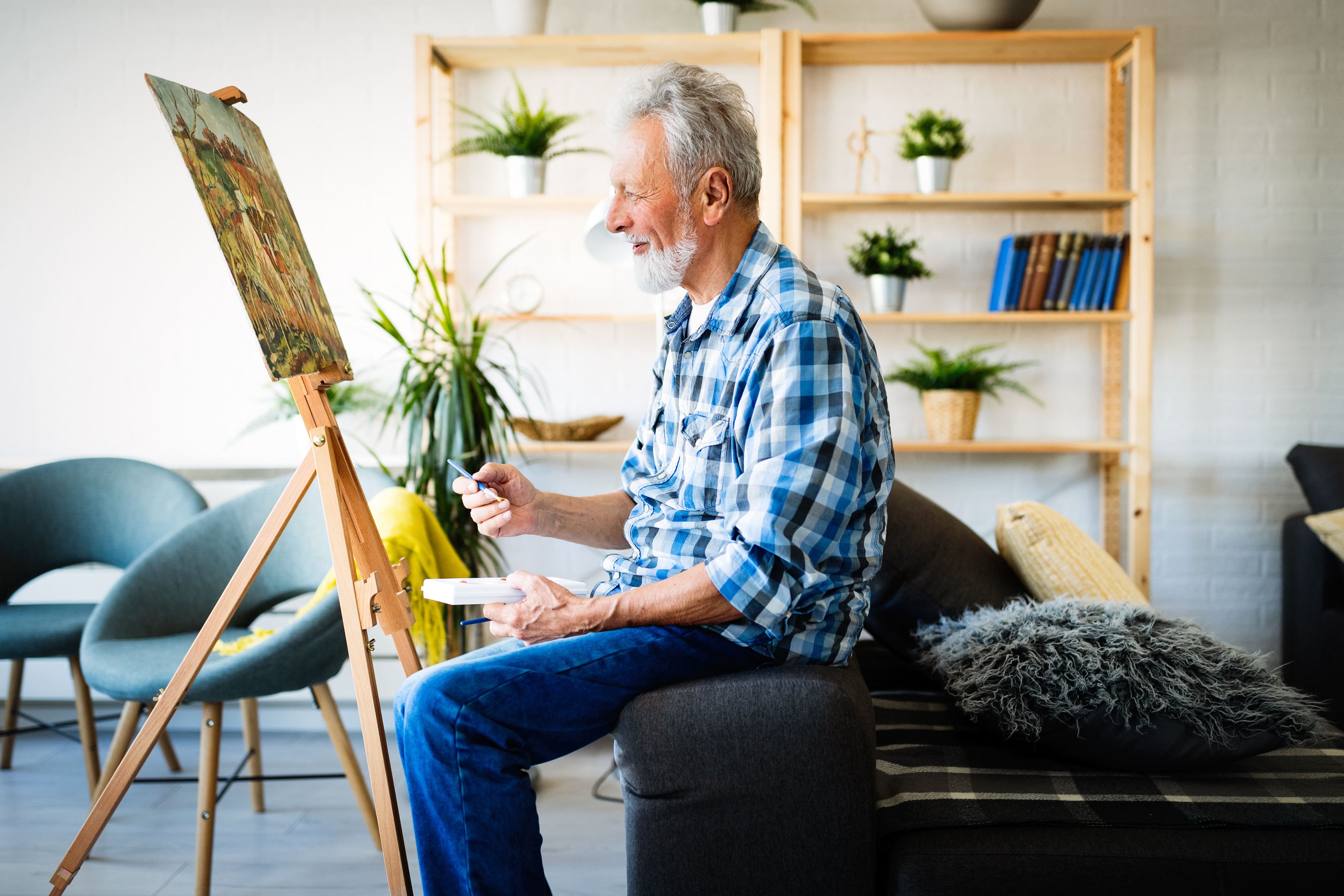 older man smiling while he paints