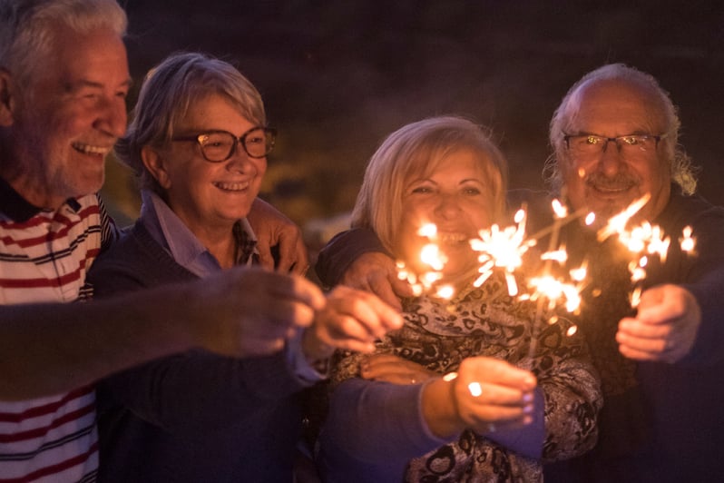 A group of friends holding sparklers at night.