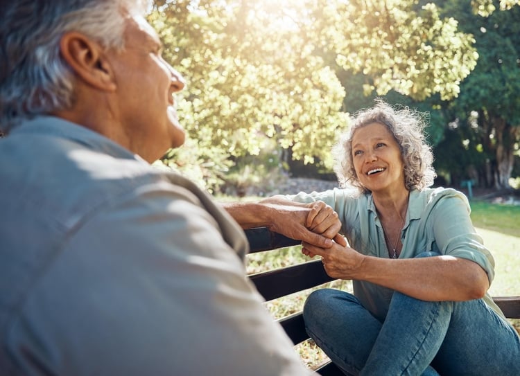 senior couple holding hands on bench outside