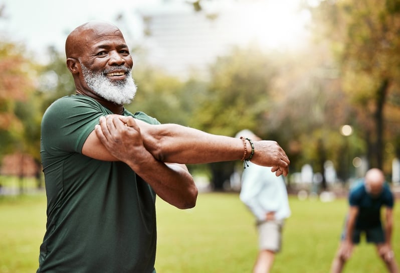 man smiling and stretching outside in yard