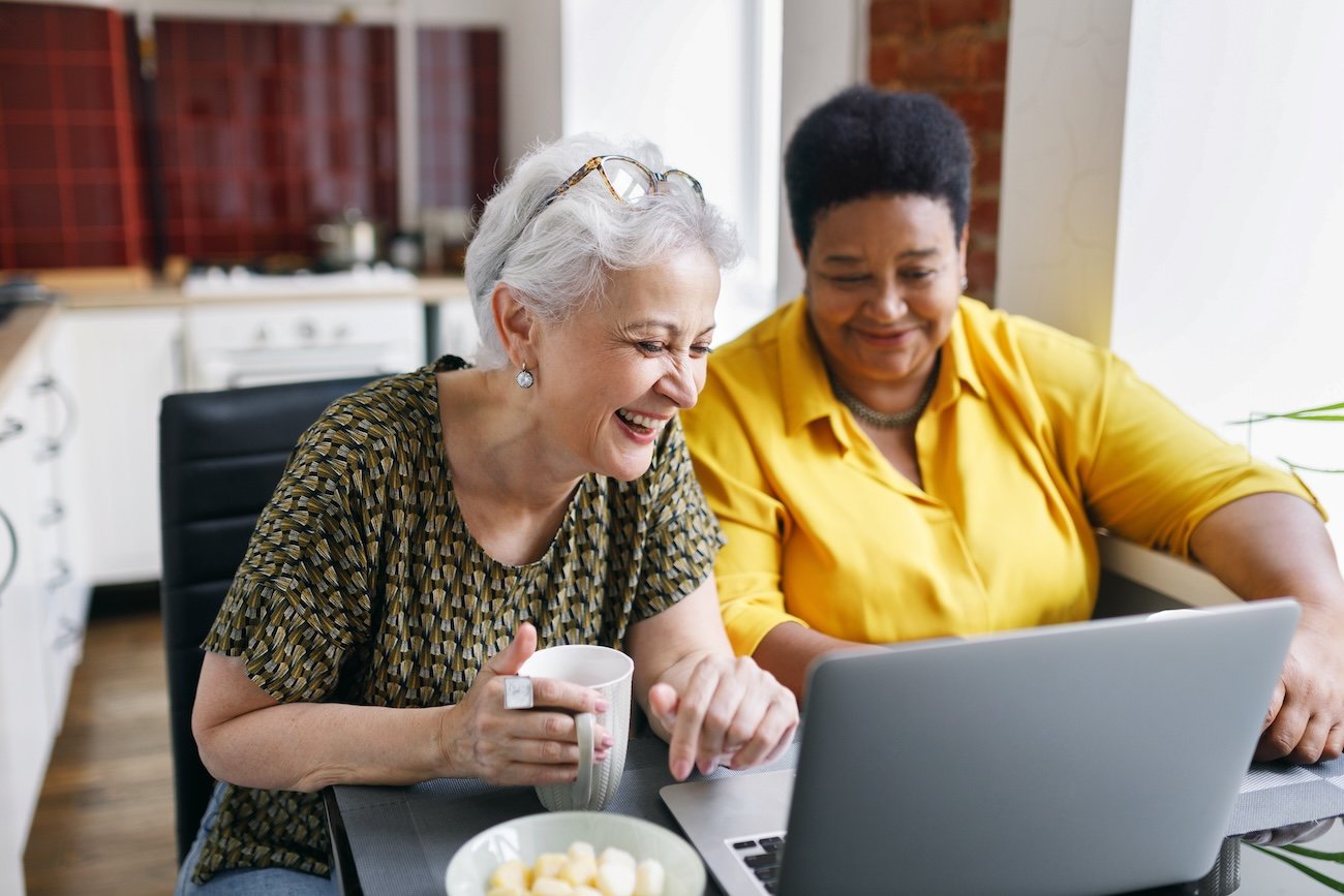 two women smiling and looking at laptop