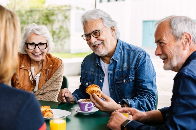 group of seniors at a cafe eating pastries and drinking coffee while talking