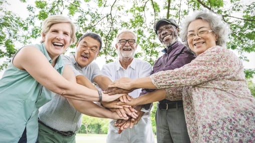 Group of five senior friends with their hands on top of each other in the middle