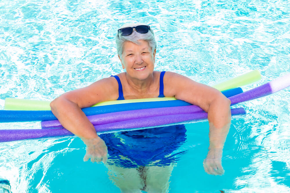 Senior woman in the pool with colorful pool noodles
