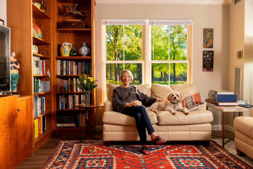 A senior resident and her dog sitting on her couch.