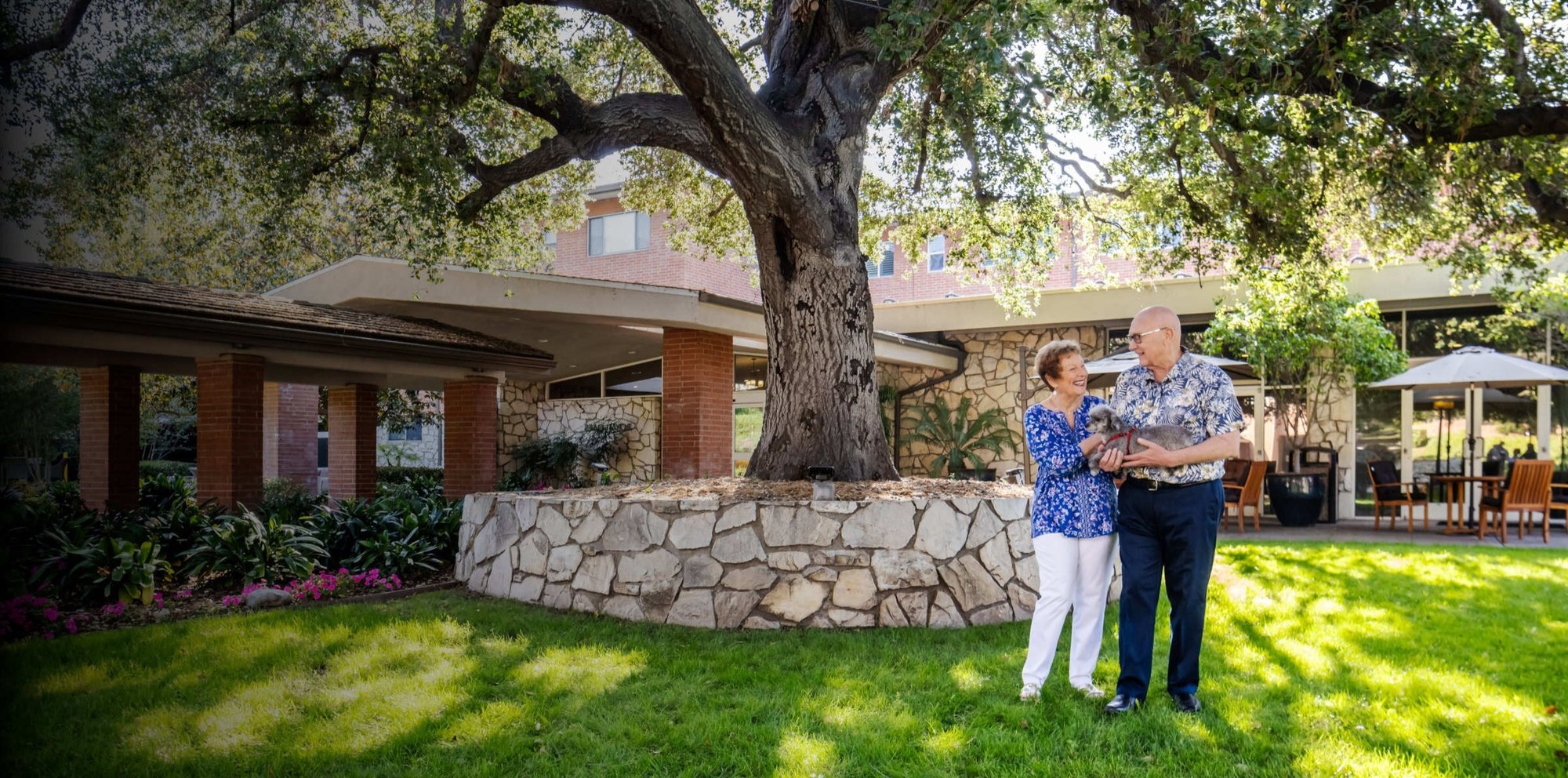 Two residents holding a dog in front of Royal Oaks community