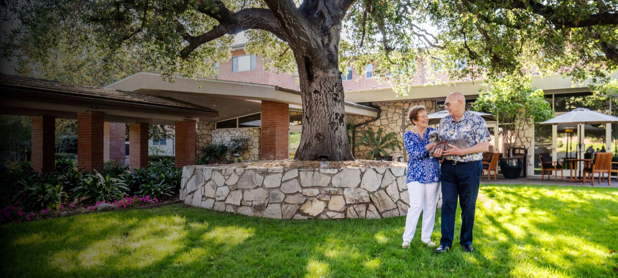 Two residents holding a dog in front of Royal Oaks community