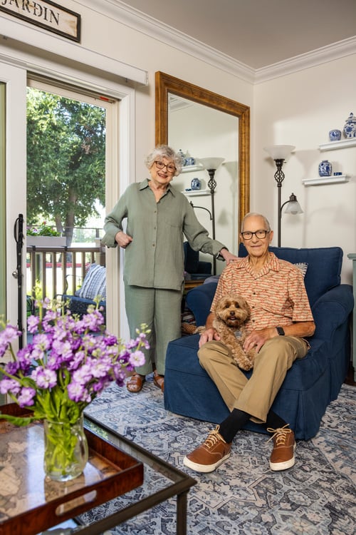 Senior couple sitting in their apartment and holding a small dog