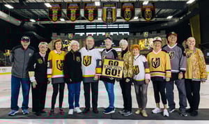 seniors posing with local hockey player inside the ice rink