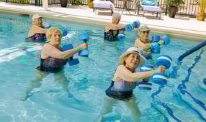 seniors holding weights while water exercising
