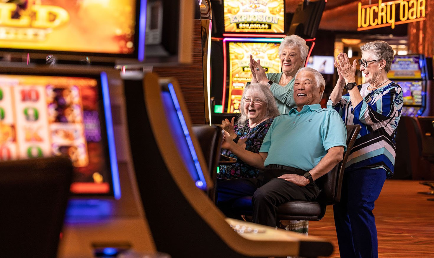 Three senior women and a senior man around a slot machine at a casino