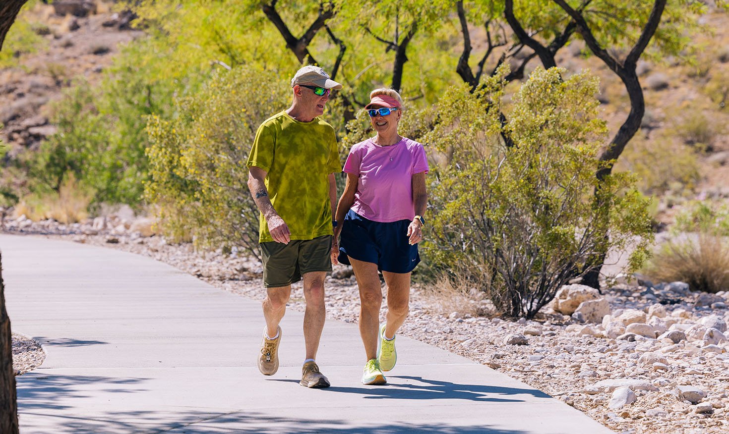 Senior man and woman in workout gear walking on a trail outside