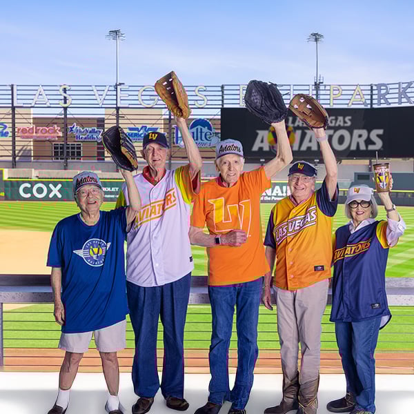 Five seniors holding up baseball gloves at Las Vegas Park, a baseball stadium