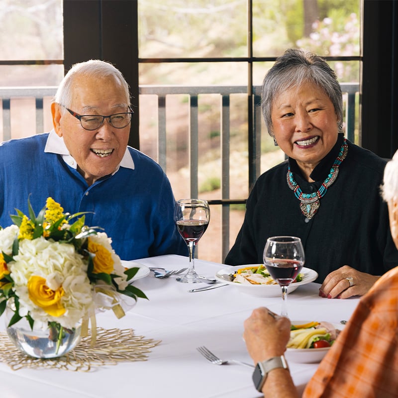 Three seniors enjoying dinner and wine in the dining venue at Las Ventanas