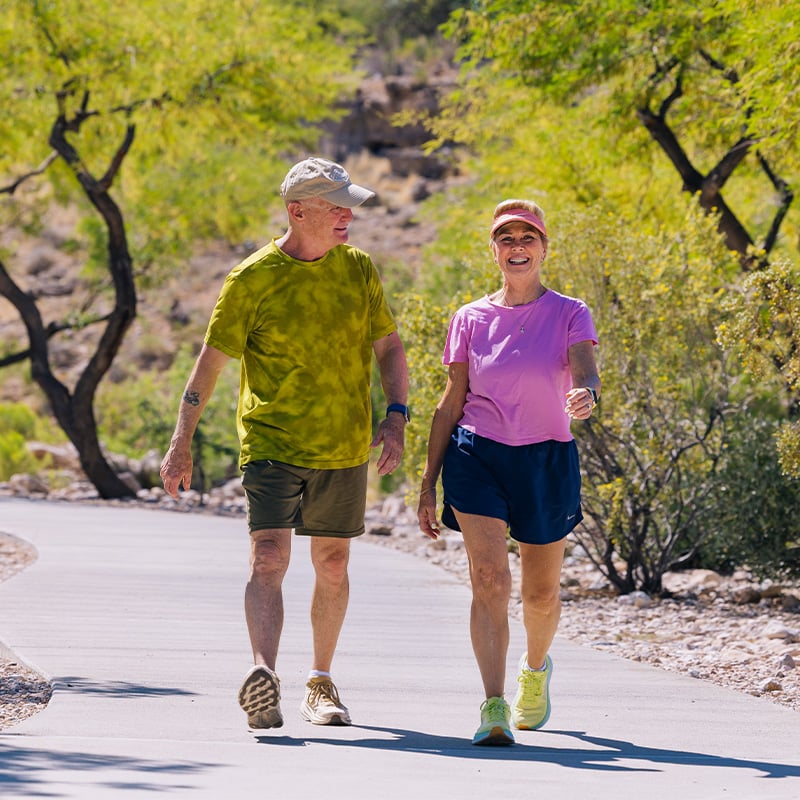 Senior man and woman in workout gear walking on a trail outside
