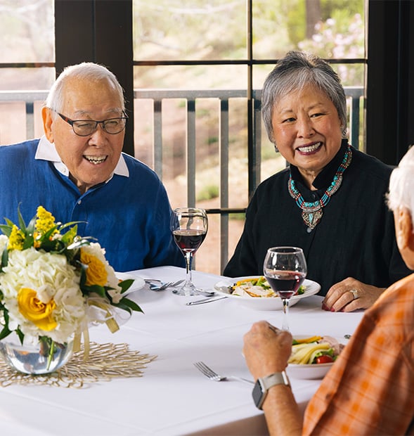 Three seniors enjoying dinner and wine in the dining venue at Las Ventanas