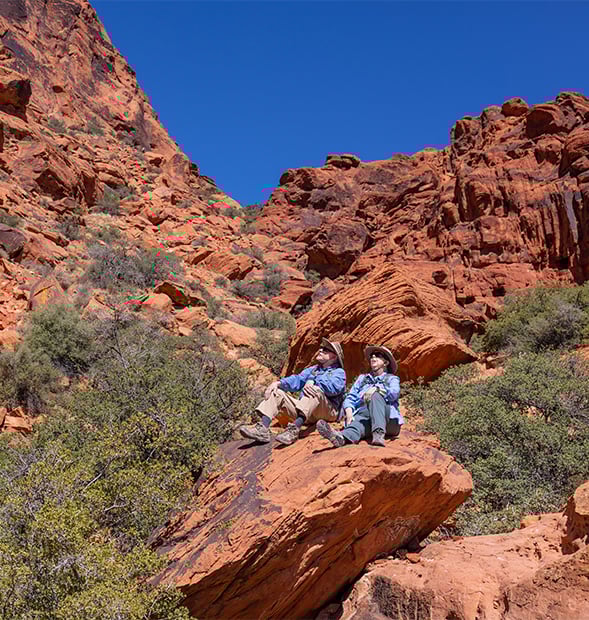 Two seniors sitting on a large rock in Red Rock Canyon