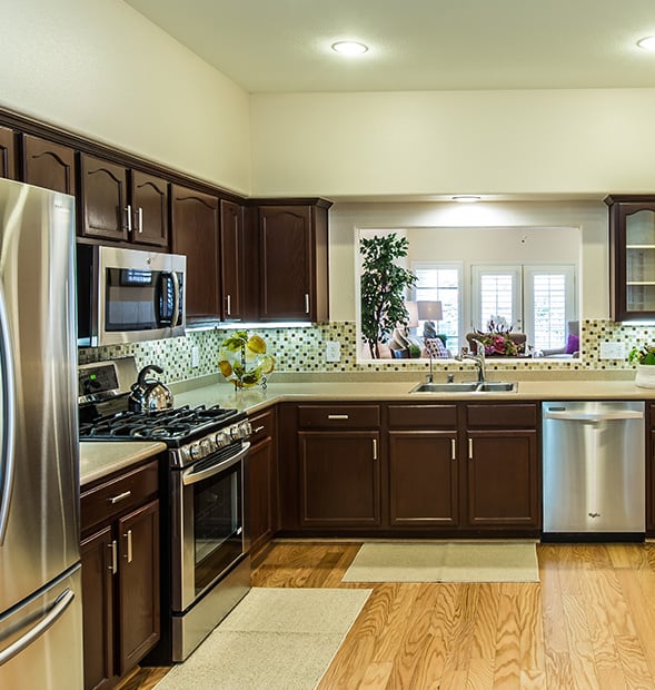 Kitchen with dark wood cabinets and stainless steel appliances of an apartment at Las Ventanas at Summerlin