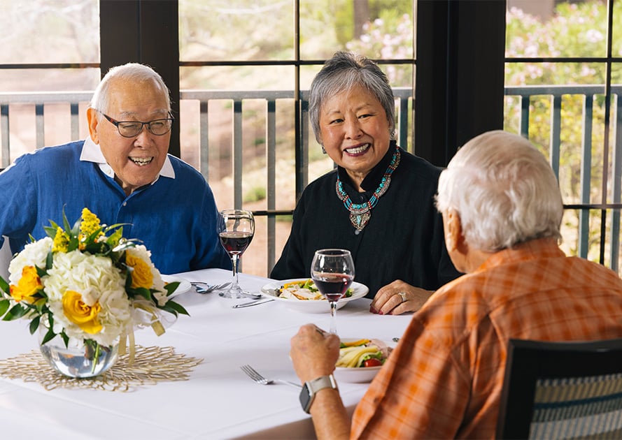 Three seniors enjoying dinner and wine in the dining venue at Las Ventanas