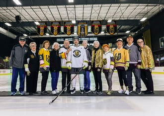 Group of seniors posing with a player for the Vegas Golden Knights in the middle of the ice rink
