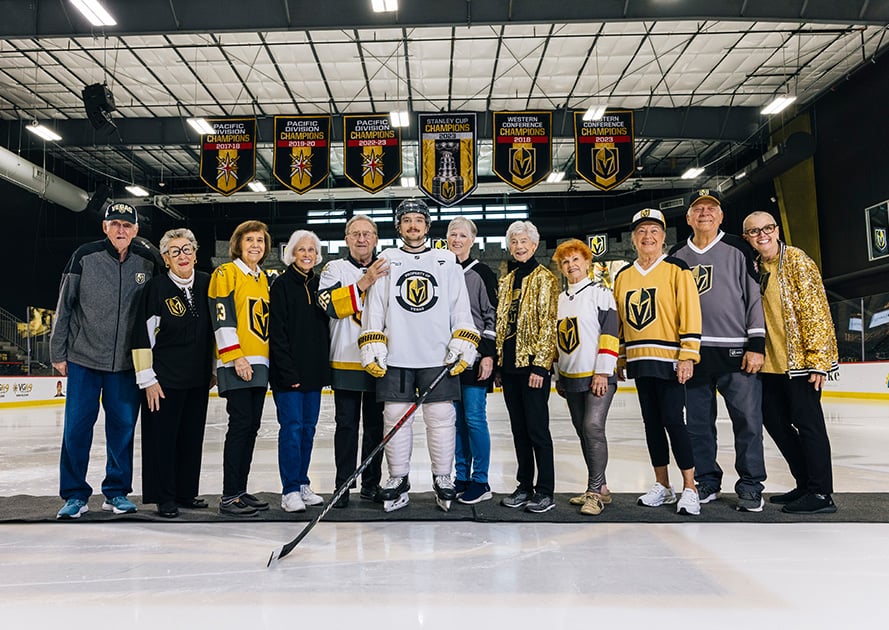 Group of seniors posing with a player for the Vegas Golden Knights in the middle of the ice rink