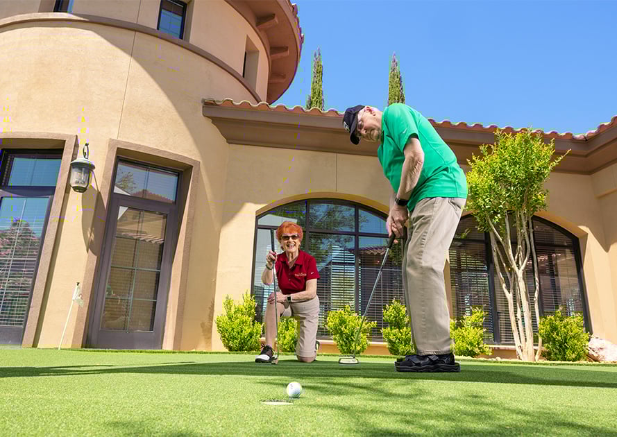 Senior man putting a golf ball on the putting green while a senior woman watches