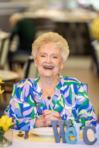 Nancy smiling while sitting at a table